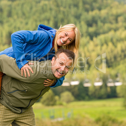 Couple having piggyback ride outside green nature
