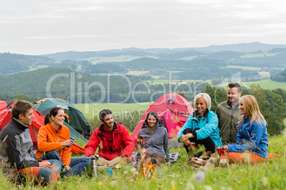 Sitting camping friends with tents and landscape