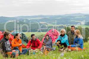 Sitting camping friends with tents and landscape