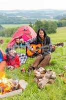 Camping friends lying tents girl playing guitar