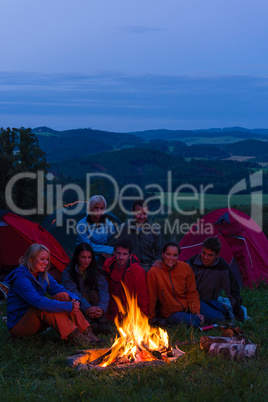 In dark camper friends sitting around fire