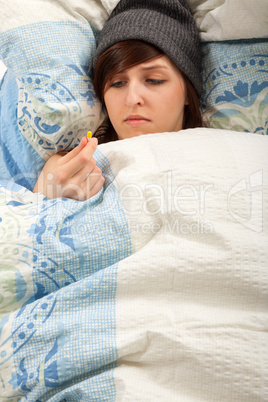 Das junge Mädchen liegt krank im Bett und nimmt ihre Medizin