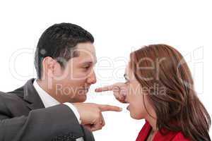 Young couple pointing at each other against a white background