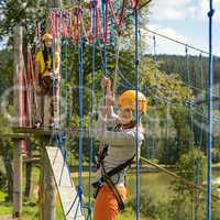 Woman climbing rope ladder in adventure park