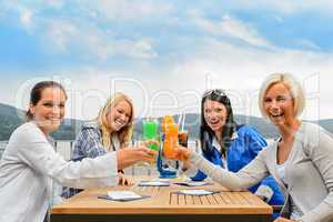 Women toasting cocktails outdoor restaurant terrace