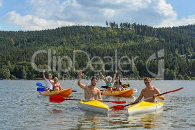 Waving cheerful friends in kayaks summer