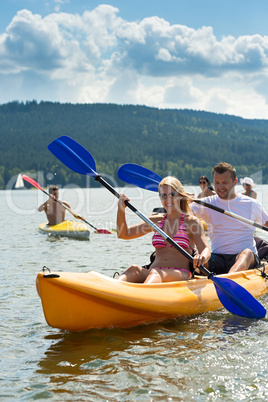 Smiling couple rowing kayak sunshine