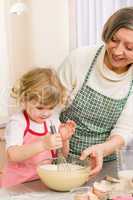 Grandmother and granddaughter whisk dough