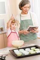 Funny little girl baking cupcake with grandma
