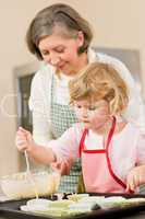 Woman and little girl baking cupcakes together