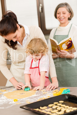 Little girl with mother cutting out cookies