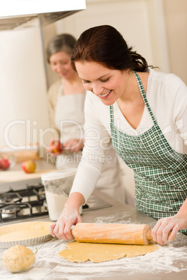 Happy woman making dough for apple pie