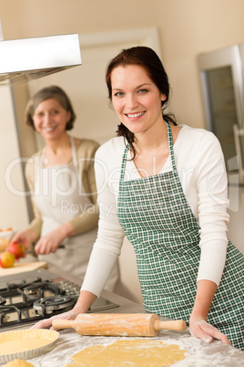 Happy woman making dough for apple pie