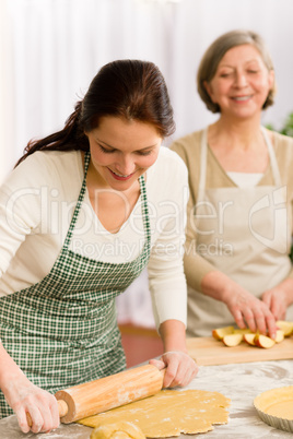 Happy woman making dough for apple pie