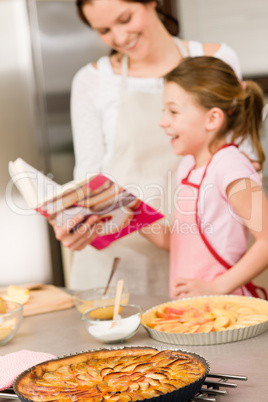 Mother and daughter look baking cookbook
