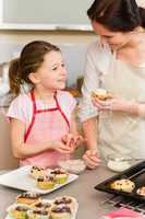 Daughter and mother decorating cupcakes sprinkles