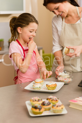 Little girl taste sprinkles decorating cupcake