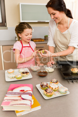 Daughter and mother decorating cupcakes sprinkles
