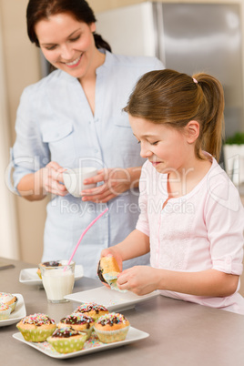 Little girl taste sprinkles cupcakes with mum