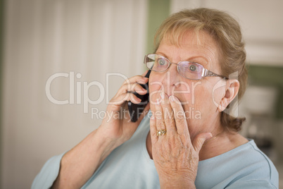 Shocked Senior Adult Woman on Cell Phone in Kitchen