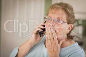 Shocked Senior Adult Woman on Cell Phone in Kitchen