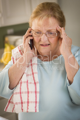 Shocked Senior Adult Woman on Cell Phone in Kitchen