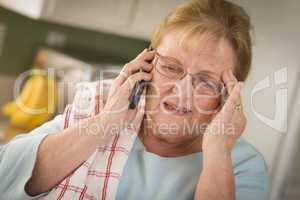 Shocked Senior Adult Woman on Cell Phone in Kitchen