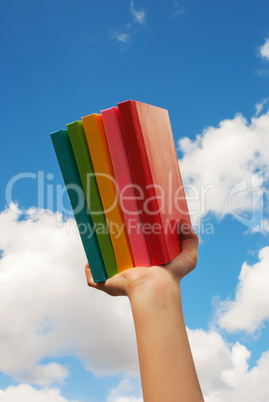 Hands holding colorful hard cover books