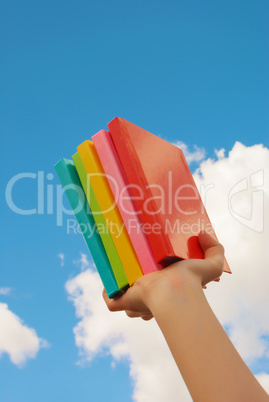 Hands holding colorful hard cover books