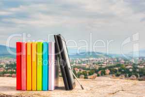 Stack of colorful books with e-book reader