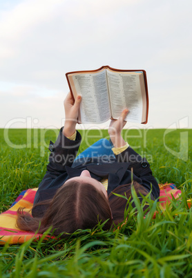 teen girl reading the bible outdoors