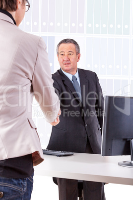 Businessman in office ranges woman's hand