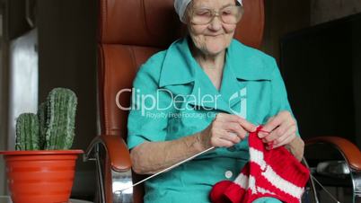 old woman sitting on chair and knitting