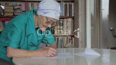 old woman in glasses writing letter