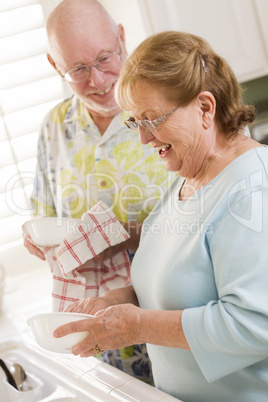 Senior Adult Couple Washing Dishes Together Inside Kitchen