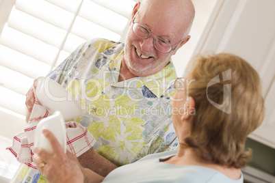 Senior Adult Couple Washing Dishes Together Inside Kitchen