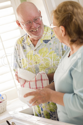 Senior Adult Couple Washing Dishes Together Inside Kitchen