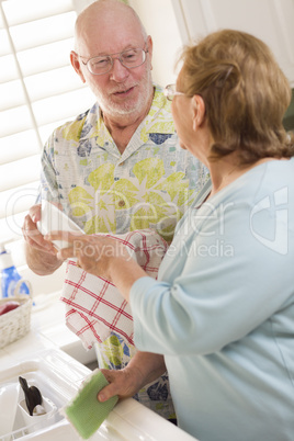 Senior Adult Couple Washing Dishes Together Inside Kitchen