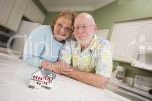 Senior Adult Couple Gazing Over Small Model Home on Counter