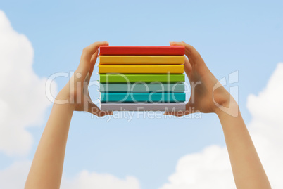 Hands holding colorful hard cover books