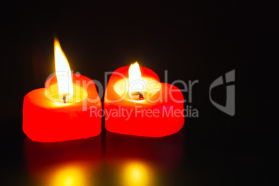 Two heart shaped burning candles