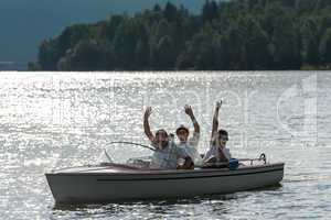 Waving men sitting in motorboat back lit