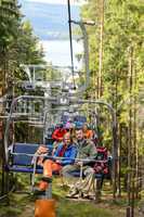 Young couple sitting on chairlift forest