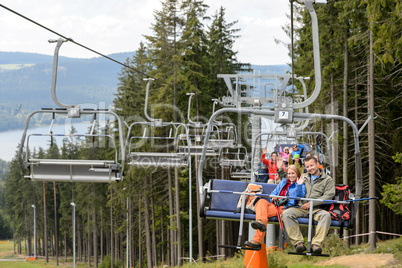 Waving young people sitting on chairlift