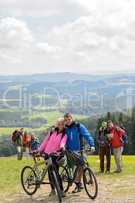 Posing cyclist couple on mountain with bikes