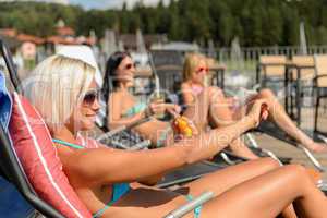 Young women lying on deckchair applying sunscreen