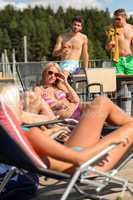 Women sunbathing on deckchair guys drinking beer