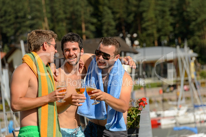 Young laughing guys in swimsuits drinking beer