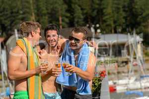 Young laughing guys in swimsuits drinking beer