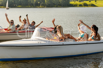 Waving friends sitting in motorboats summertime